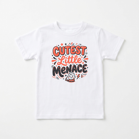 A white short-sleeve kids' t-shirt with a colorful graphic on the chest that reads 'CUTEST LITTLE MENACE' in orange and black lettering with a small cartoon character below, displayed flat against a light off-white background.