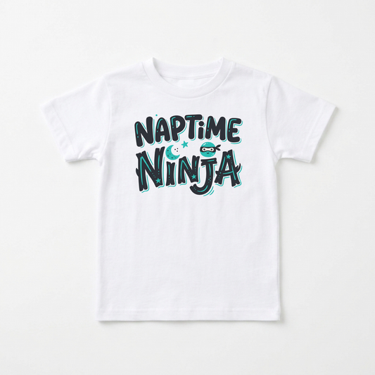 A white kids' short-sleeve t-shirt with a playful graphic reading 'NAPTIME NINJA' in dark teal and light blue bubble letters, featuring a small cartoon ninja character.