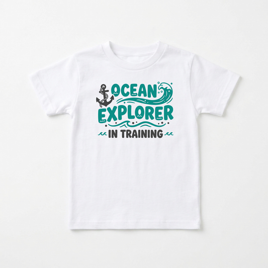 A white short-sleeve kids' t-shirt with a graphic on the chest that reads 'OCEAN EXPLORER IN TRAINING' in teal and black, featuring an anchor and wave illustration.