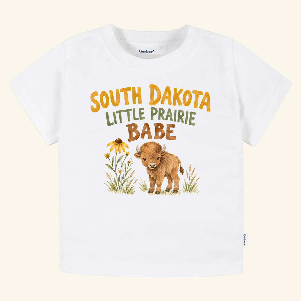 White toddler t-shirt featuring a watercolor illustration of a bison calf and wildflowers, with South Dakota Little Prairie Babe printed above, styled as a South Dakota Toddler Shirt – Little Prairie Babe Buffalo Tee by Toodleroos.