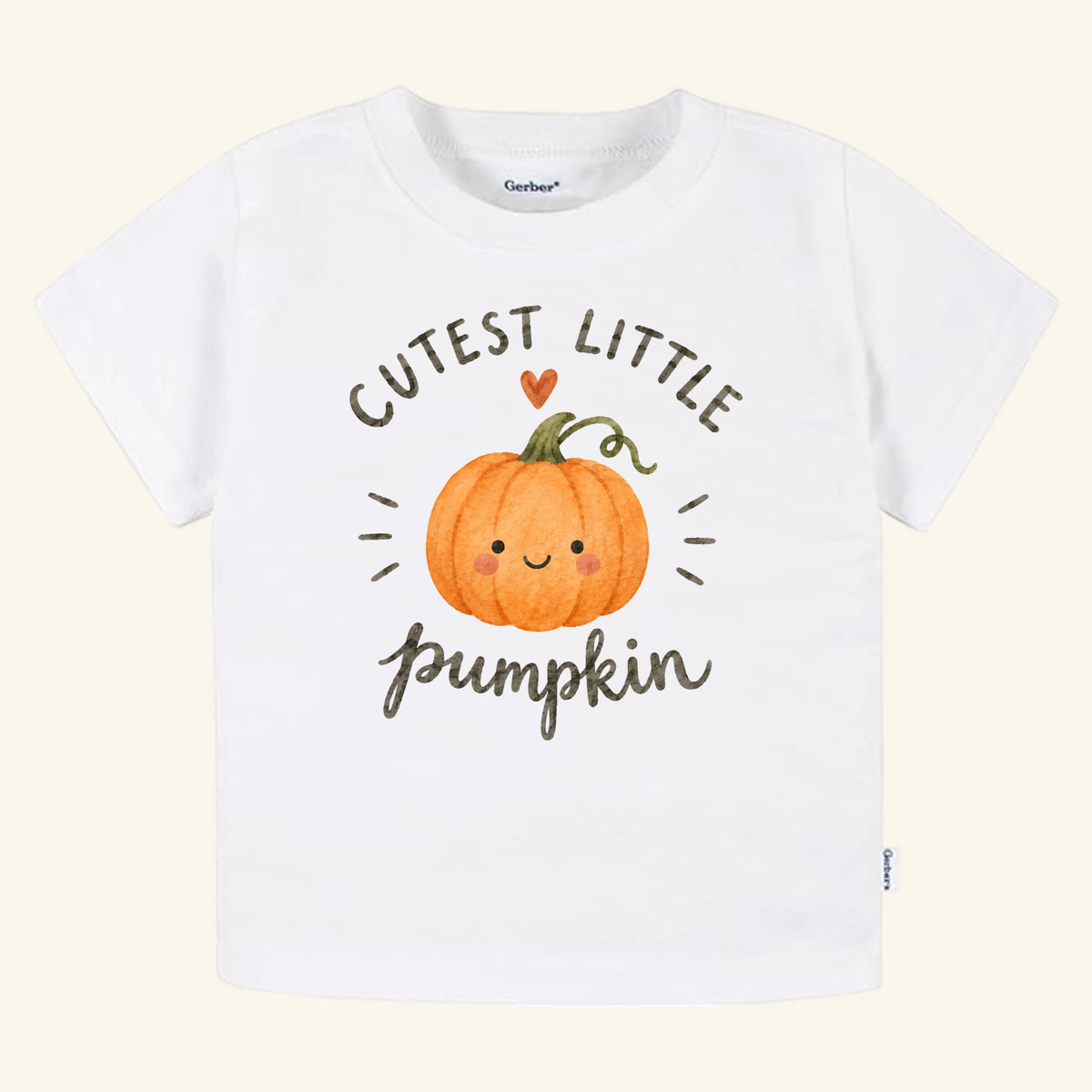 Toodleroos Cutest Little Pumpkin Toddler Shirt featuring a white tee with a watercolor pumpkin with a smiling face, the text CUTEST LITTLE pumpkin, and a small heart above.
