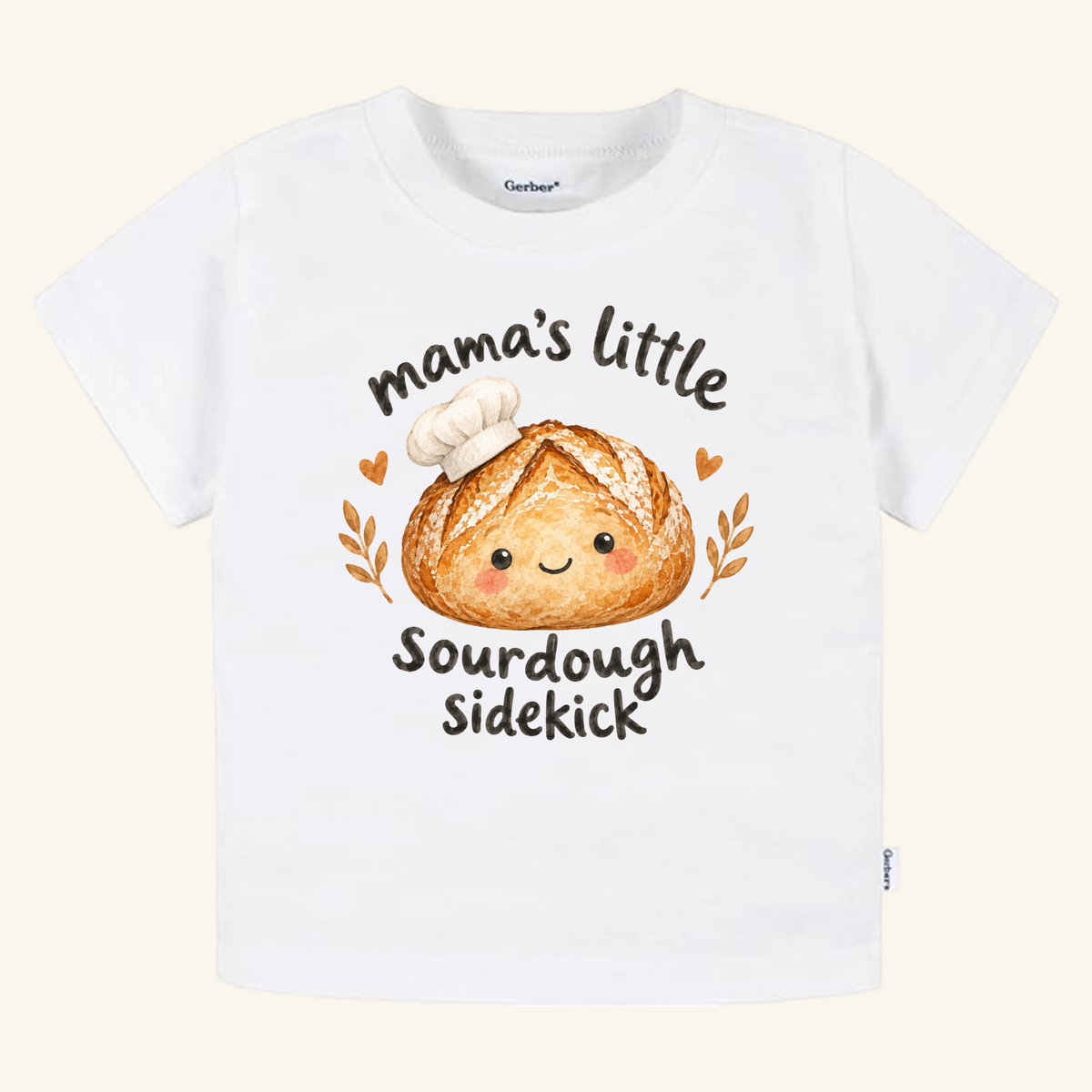 White toddler Toodleroos Mama’s Little Sourdough Sidekick Toddler Shirt featuring a cute illustration of a smiling sourdough loaf with a chef’s hat and the text Mama’s Little Sourdough Sidekick.