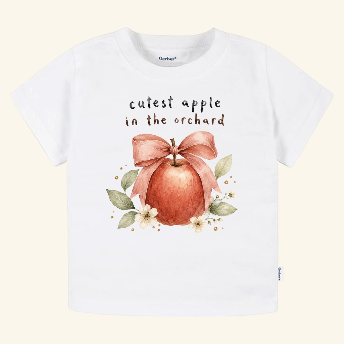 White toddler Cutest Apple in the Orchard Toddler Shirt – Fall Apple Bow Tee featuring a watercolor illustration of an apple with a bow, surrounded by leaves and small flowers, with cutest apple in the orchard printed above.