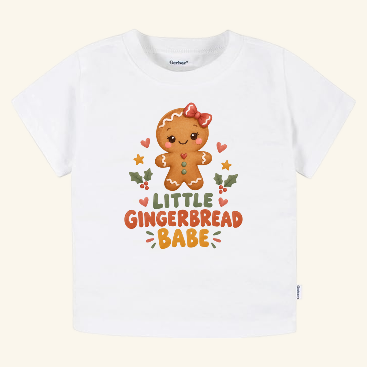 Little Gingerbread Babe Toddler Shirt featuring a white t-shirt with a cartoon gingerbread character wearing a red hair bow, surrounded by holly and hearts, with the text LITTLE GINGERBREAD BABE.