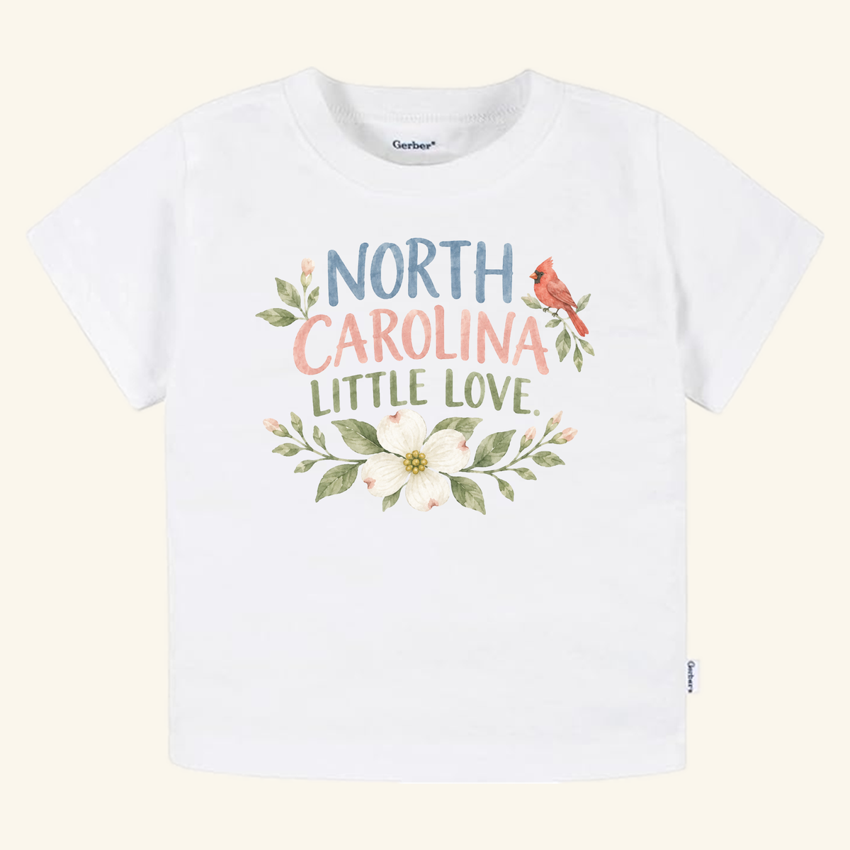 North Carolina Toddler Shirt – Little Love Dogwood & Cardinal Tee featuring the text North Carolina Little Love decorated with a cardinal, a dogwood flower, and green leaves.