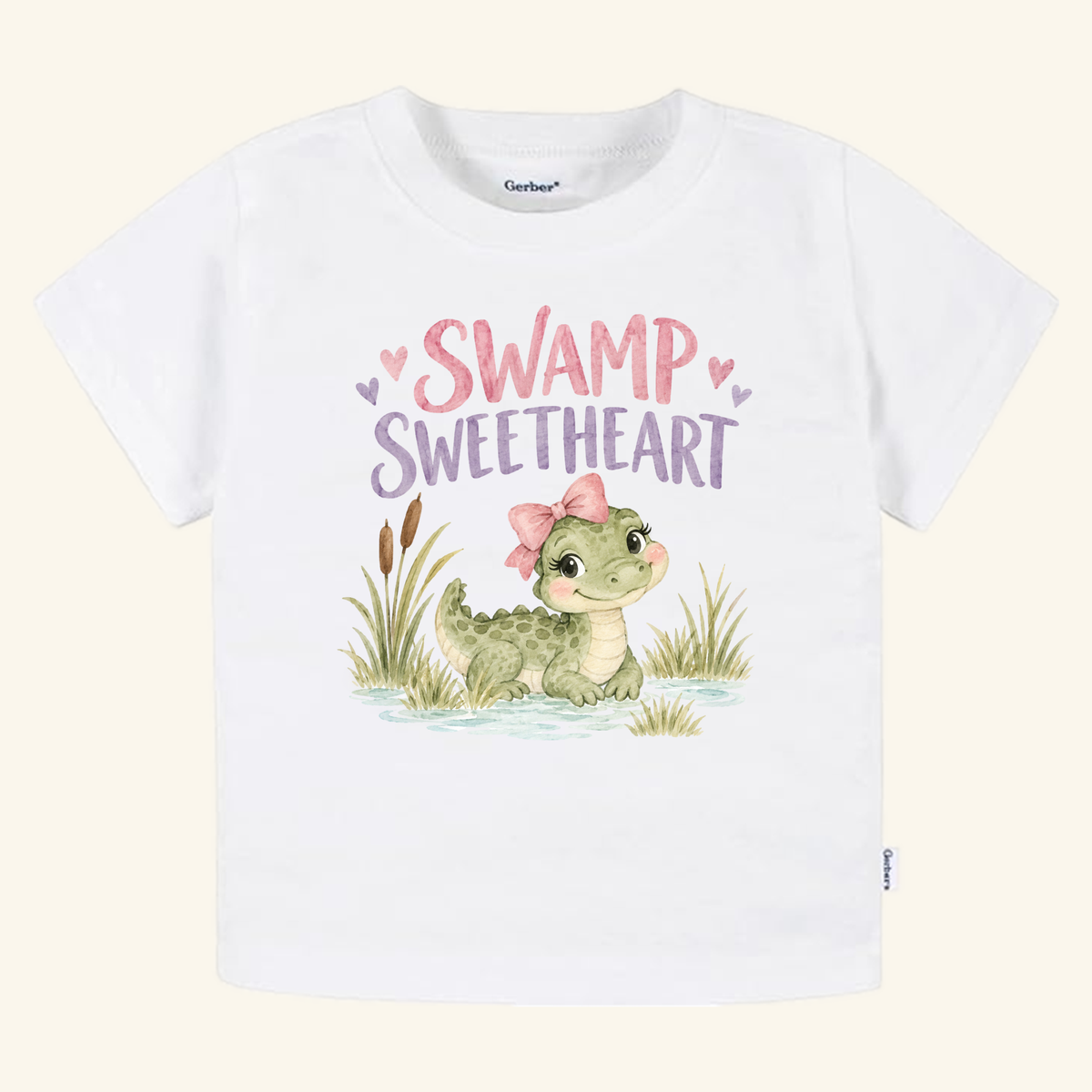 Swamp Sweetheart Toddler Shirt – Baby Alligator Girls Tee featuring a white toddler t-shirt with a watercolor illustration of a baby alligator wearing a pink bow and the text SWAMP SWEETHEART above it.