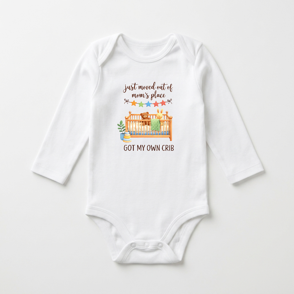 A white long-sleeve baby bodysuit with a graphic print on the chest. The graphic features a cartoon illustration of a bear and rabbit in a crib with a green blanket, accompanied by the text 'just moved out of mom's place' and 'GOT MY OWN CRIB' in brown lettering.