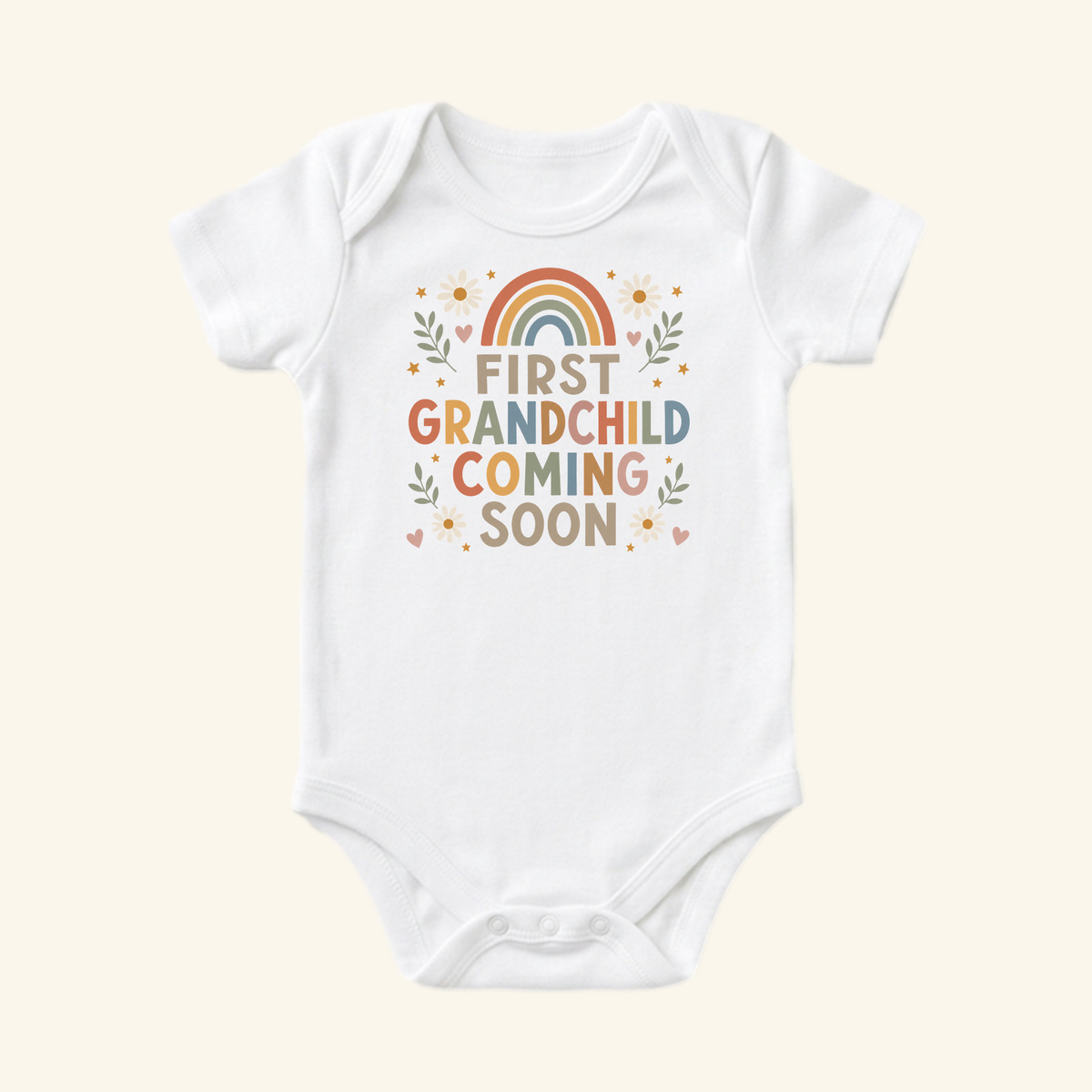 White First Grandchild Announcement Baby Onesie – Coming Soon Bodysuit featuring a rainbow, flowers, and the text First Grandchild Coming Soon, perfect for a grandparent pregnancy reveal.