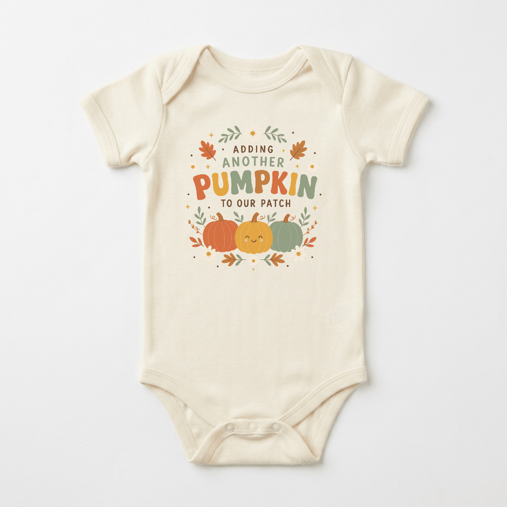 Dress your little one in the Fall Pregnancy Announcement Onesie – Adding Another Pumpkin Short-Sleeve Bodysuit from Toodleroos. This cream-colored bodysuit features a charming fall-themed design with three pumpkins and leaves, along with the phrase “Adding another pumpkin to our patch” in orange, green, and brown lettering. It’s an adorable way to share your exciting news and makes the perfect choice for a fall pregnancy announcement!.