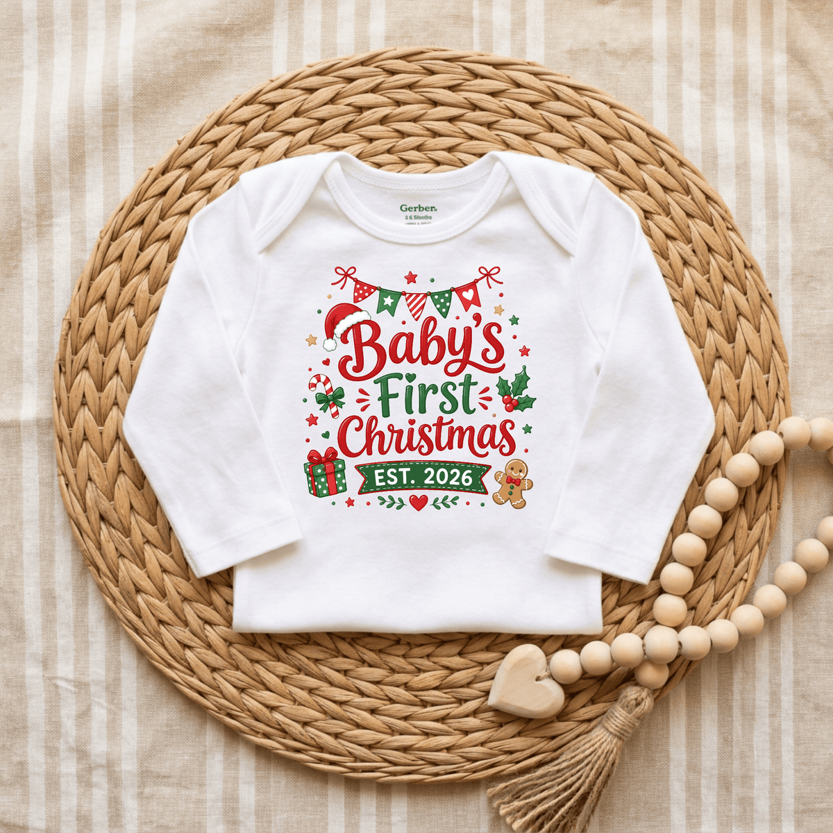 The Toodleroos Baby’s First Christmas Est. 2026 Long Sleeve Onesie – Holiday Keepsake Bodysuit features festive red and green lettering that says “Baby’s First Christmas EST. 2026,” surrounded by charming holiday graphics. Displayed on a woven mat with wooden beads and a heart-shaped ornament, this adorable bodysuit is the perfect 2026 Christmas outfit for your little one’s special first celebration.
