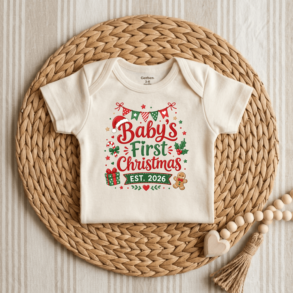 Introducing the Toodleroos Baby’s First Christmas Est. 2026 Long Sleeve Onesie – a cream-colored holiday keepsake bodysuit featuring “Baby’s First Christmas Est. 2026” in festive red and green, accented with charming stars, a gift, candy cane, and gingerbread motif. Displayed on a woven mat, this cozy onesie is the perfect 2026 Christmas outfit to celebrate your little one’s special milestone.