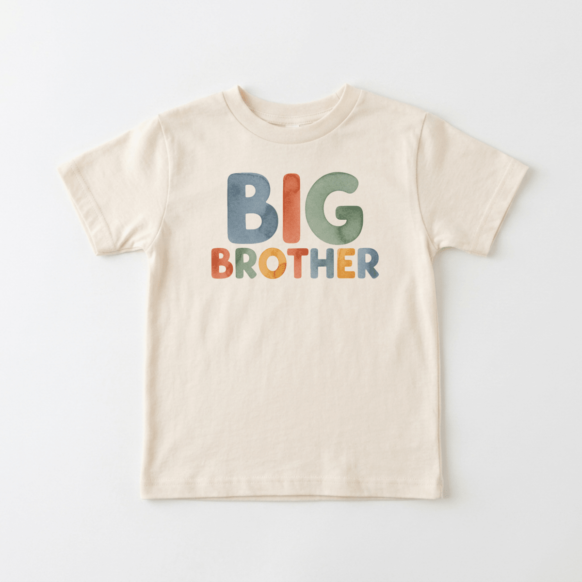 The Toodleroos Big Brother Toddler Shirt – Colorful Retro Design features bold, vibrant “BIG BROTHER” lettering across the front of a beige shirt, laid flat on a white background—perfect as a fun big brother shirt or a memorable pregnancy announcement shirt.