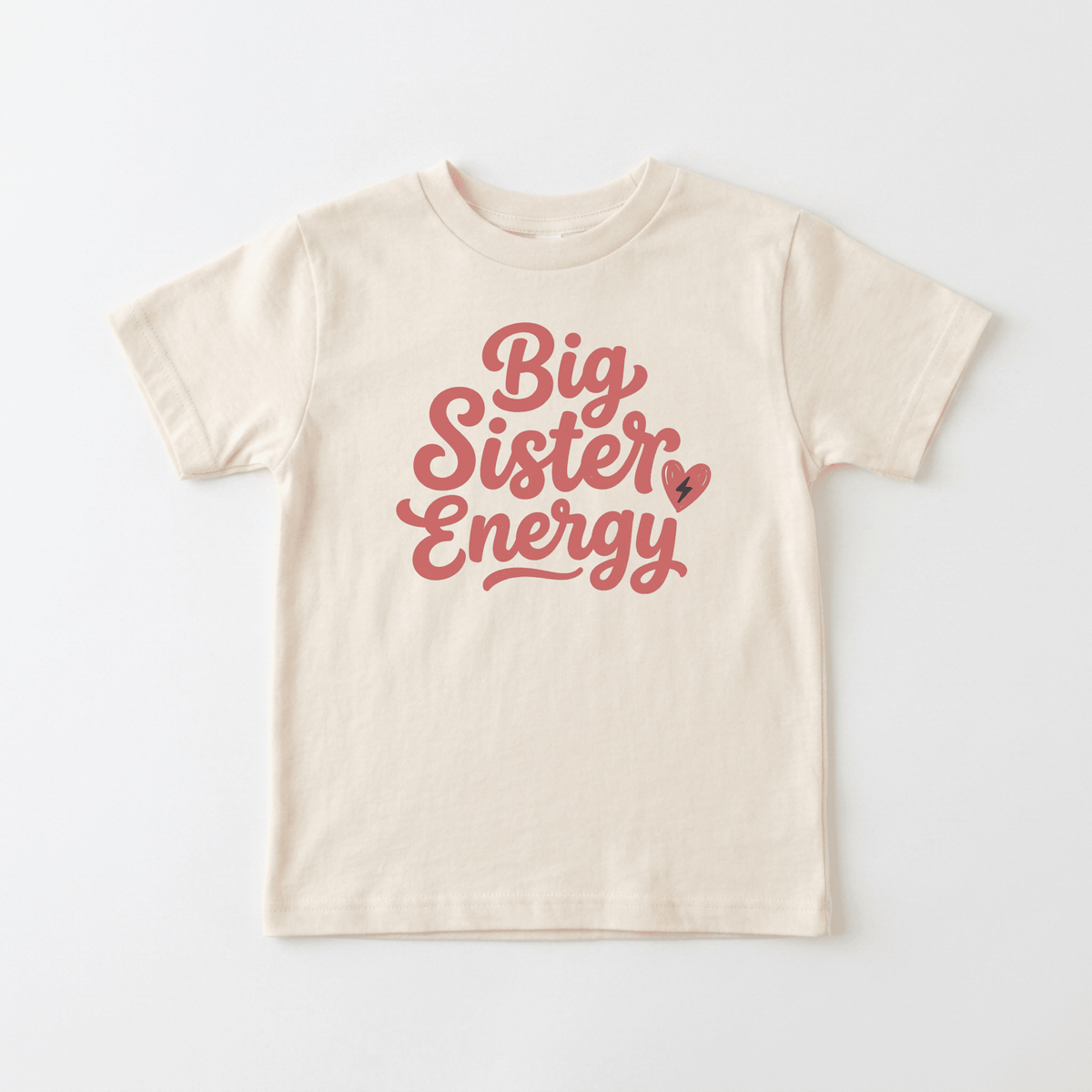 Dress your little one in the Toodleroos Big Sister Energy Toddler Shirt – Confident Sibling Tee, a beige toddler top with playful pink cursive that reads “Big Sister Energy,” accented by a cute heart and lightning bolt graphic next to “Sister”—perfect for celebrating new big sisters.