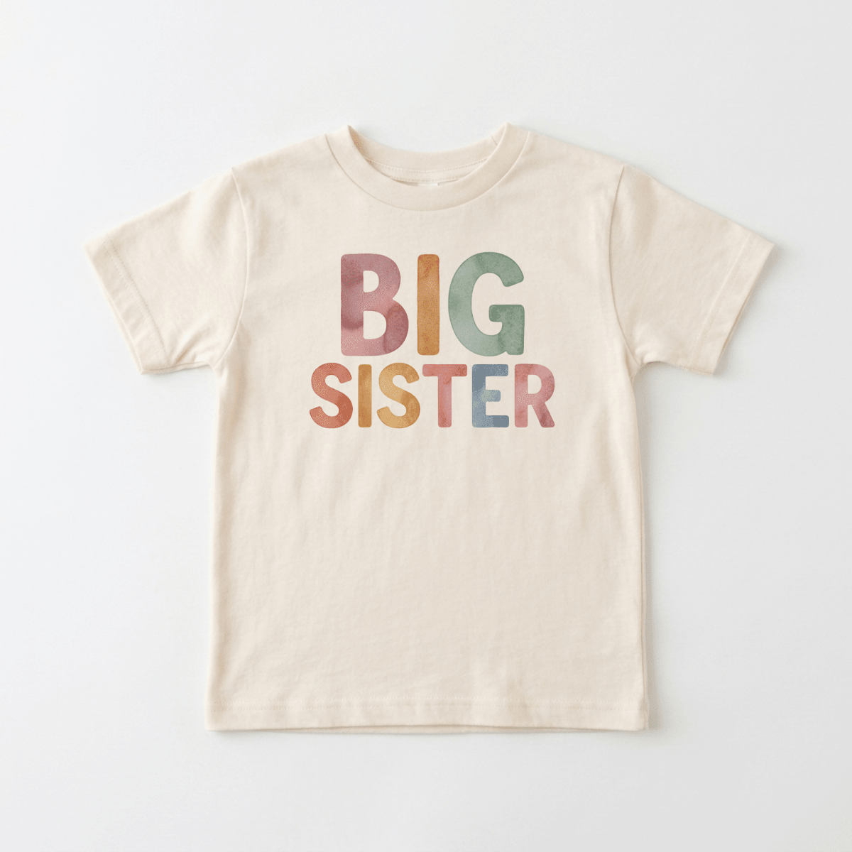 The Toodleroos Big Sister Toddler Shirt – Colorful Retro Design features a cream-colored fabric with “BIG SISTER” boldly printed in large, pastel, retro-inspired letters across the front—perfect for toddlers or as an adorable pregnancy announcement—shown here on a plain white background.
