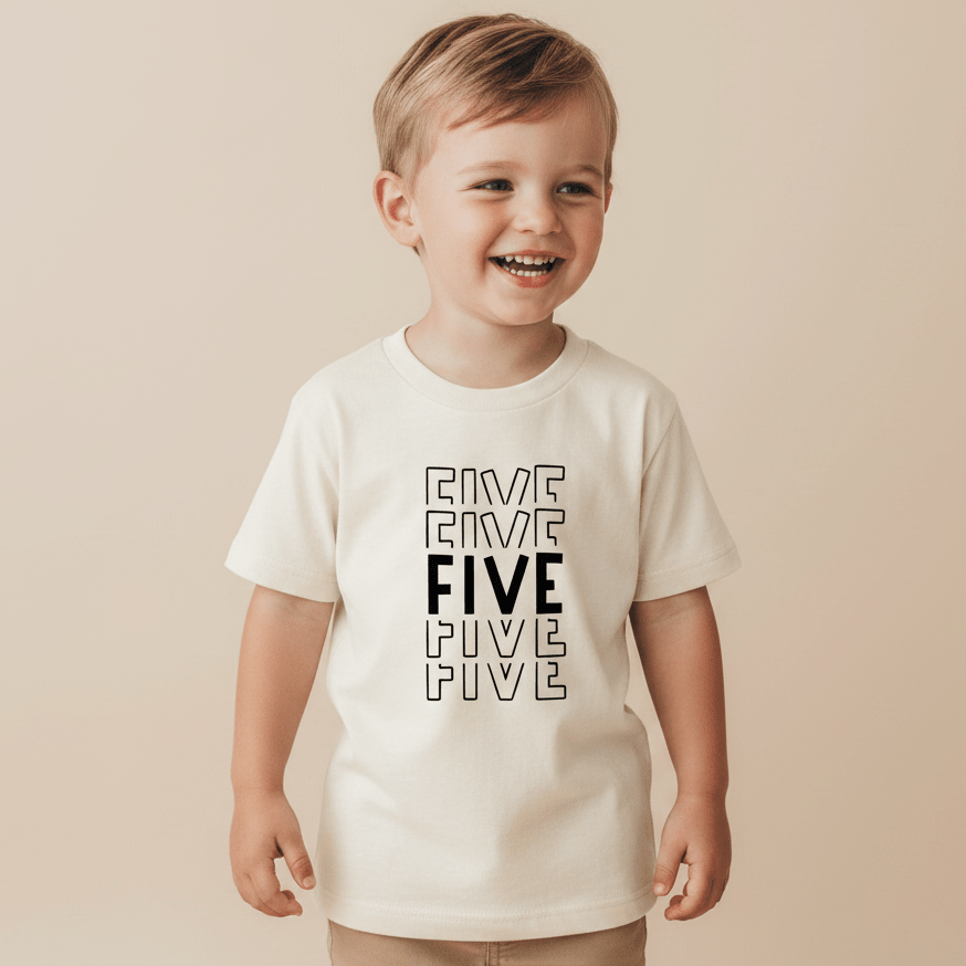A happy young child wears the Toodleroos Bold 5th Birthday Kids Shirt – a white tee featuring the word “FIVE” printed five times in bold, outlined letters—making it a perfect gender-neutral birthday shirt for celebrating their fifth birthday.
