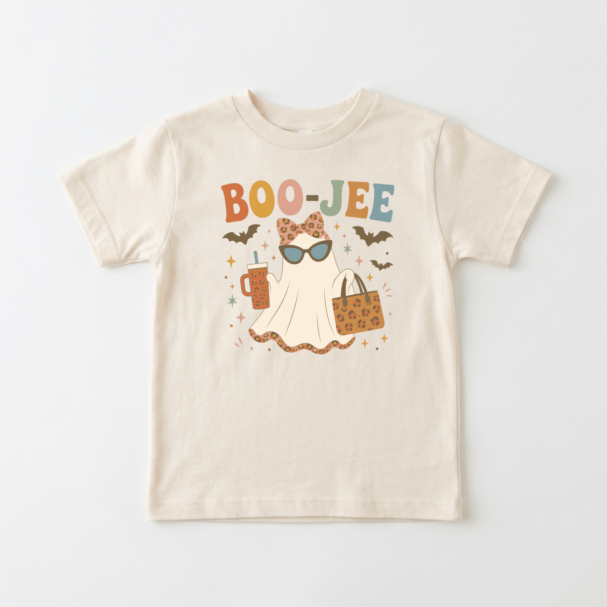 Introducing the Toddler Girl Halloween Shirt – Boo-Jee Ghost Short-Sleeve Tee from Toodleroos! This adorable beige shirt showcases a trendy ghost wearing sunglasses, holding a drink and a leopard-print bag, all surrounded by playful bats and stars. The vibrant text “BOO-JEE” appears above in colorful letters—making it the perfect Cute Halloween Outfit or an adorable Boo-Jee Ghost Shirt for your little one.
