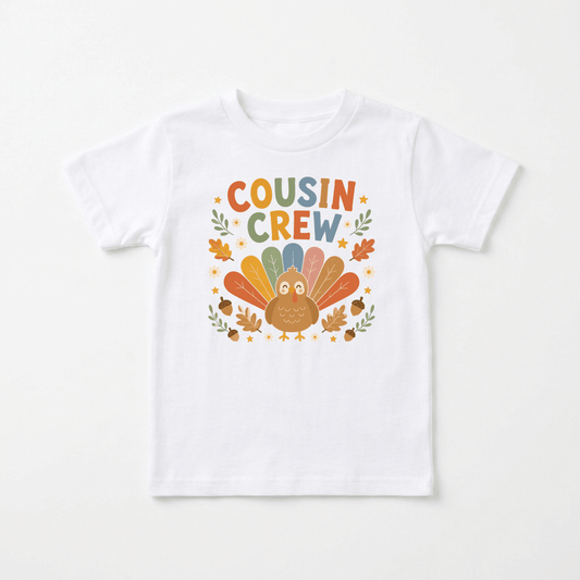 Introducing the Toodleroos Thanksgiving Cousin Shirt – Cousin Crew Turkey Toddler Tee: a white T-shirt featuring a vibrant cartoon turkey, autumn leaves, and bold “Cousin Crew” lettering above the turkey. This adorable tee is perfect for family gatherings and makes an ideal toddler Thanksgiving shirt with its festive autumn and Thanksgiving-themed design.
