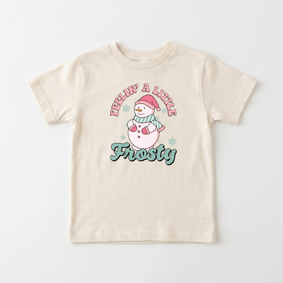 Dress your little one in the Feelin’ a Little Frosty Toddler Shirt by Toodleroos—a retro snowman tee featuring a cheerful snowman in a pink hat and scarf, “Feelin’ a Little Frosty” text above and below, and charming blue snowflakes all around. It’s the perfect vintage holiday shirt for capturing adorable moments!.