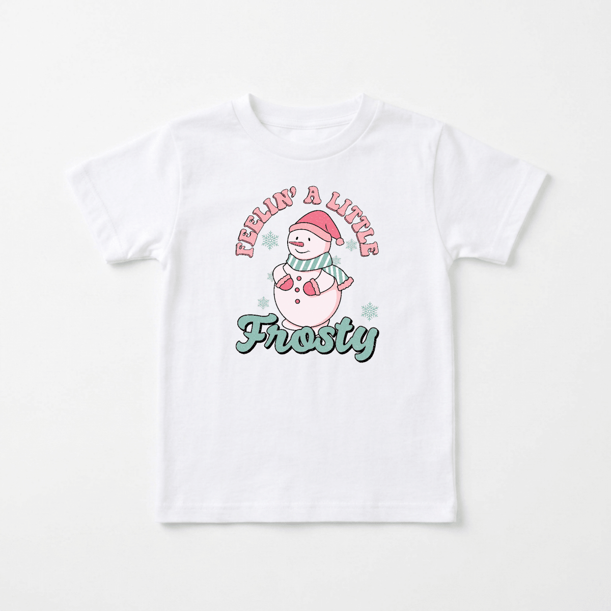 This Toodleroos “Feelin’ a Little Frosty Toddler Shirt – Retro Snowman Tee” features a white tee with a cartoon snowman wearing a Santa hat and scarf, surrounded by small snowflakes. The text “Feelin’ a Little” appears above the snowman, with “Frosty” below, making it the perfect vintage-inspired holiday shirt for toddler photos.