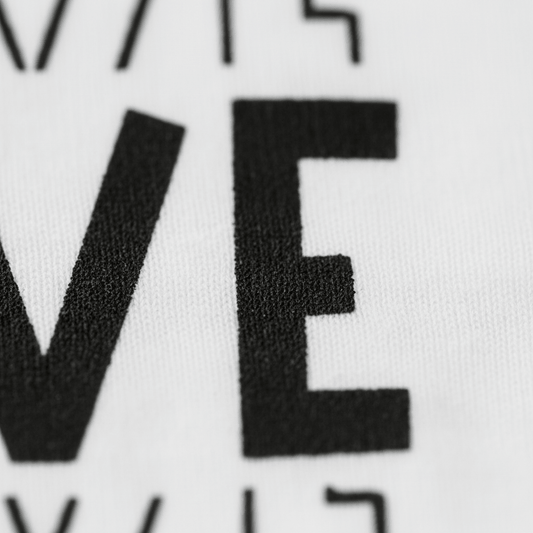 Close-up of black, bold, capital letters “VE” printed on white fabric, highlighting the detailed texture of both the textile and ink—featured on the Toodleroos Bold 5th Birthday Kids Shirt, a versatile and gender-neutral 5th birthday tee.