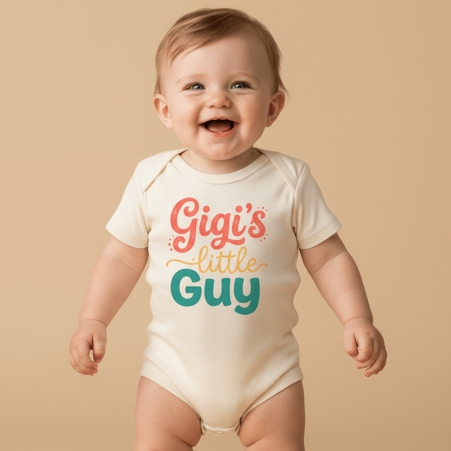 A happy baby stands against a beige background wearing the Toodleroos Gigi’s Little Guy Onesie – Baby Boy Bodysuit, featuring playful, colorful text that reads ‘Gigi’s little guy’—the perfect baby shower gift for any little boy.