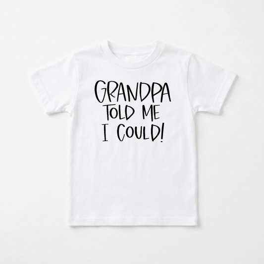 Toodleroos Grandpa Told Me I Could Toddler Shirt – Funny Family Tee in white, featuring bold black text that reads “GRANDPA TOLD ME I COULD!” is displayed on a flat, neutral background. This playful toddler shirt from Toodleroos makes an ideal gift for little ones or a humorous grandpa-themed tee perfect for family reunions.