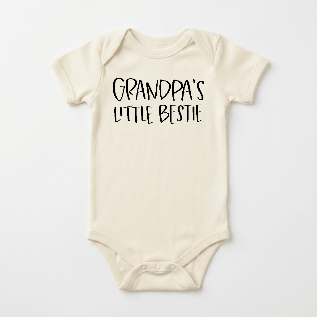 Dress your little one in the Toodleroos Grandpa’s Little Bestie Baby Onesie – a cream-colored bodysuit featuring charming black handwritten text on the chest that says “GRANDPAS LITTLE BESTIE.” This adorable grandpa-and-baby outfit has short sleeves and three snaps at the bottom, making it a thoughtful baby shower gift from Grandpa.