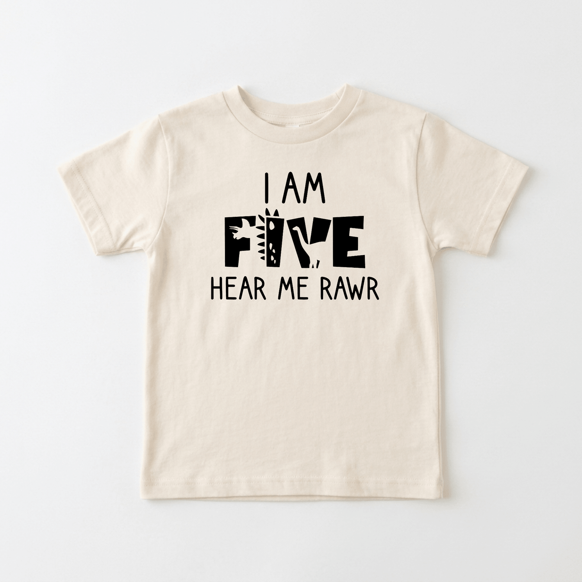 The Toodleroos “I Am Five Hear Me Rawr Kids Shirt – Dinosaur 5th Birthday Tee” is a beige dinosaur-themed shirt for kids, featuring black text that says “I am five, hear me rawr.” The word “five” is playfully decorated with dinosaur elements, making it the perfect 5th birthday or special dinosaur birthday shirt for little ones.