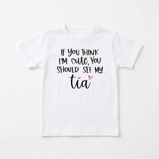 The Toodleroos “If You Think I’m Cute See My Tía” Toddler Shirt is a white children’s t-shirt featuring black text that reads “If you think I’m cute, you should see my tía,” with a small pink heart next to the word “tía.” This funny bilingual tee is the perfect gift for an aunt and makes an adorable tía toddler shirt for little ones who love their favorite aunt.