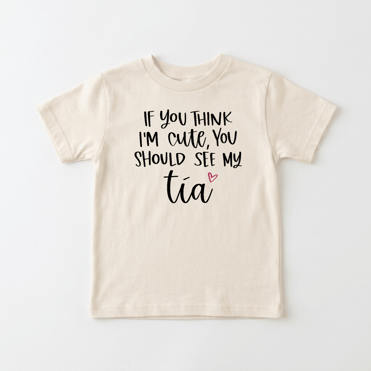 The Toodleroos “If You Think I’m Cute See My Tía” Toddler Shirt is a beige tee featuring bold black text and a small pink heart under the word tía. This funny bilingual toddler shirt makes the perfect aunt gift or adorable tee for little ones who love their aunties.