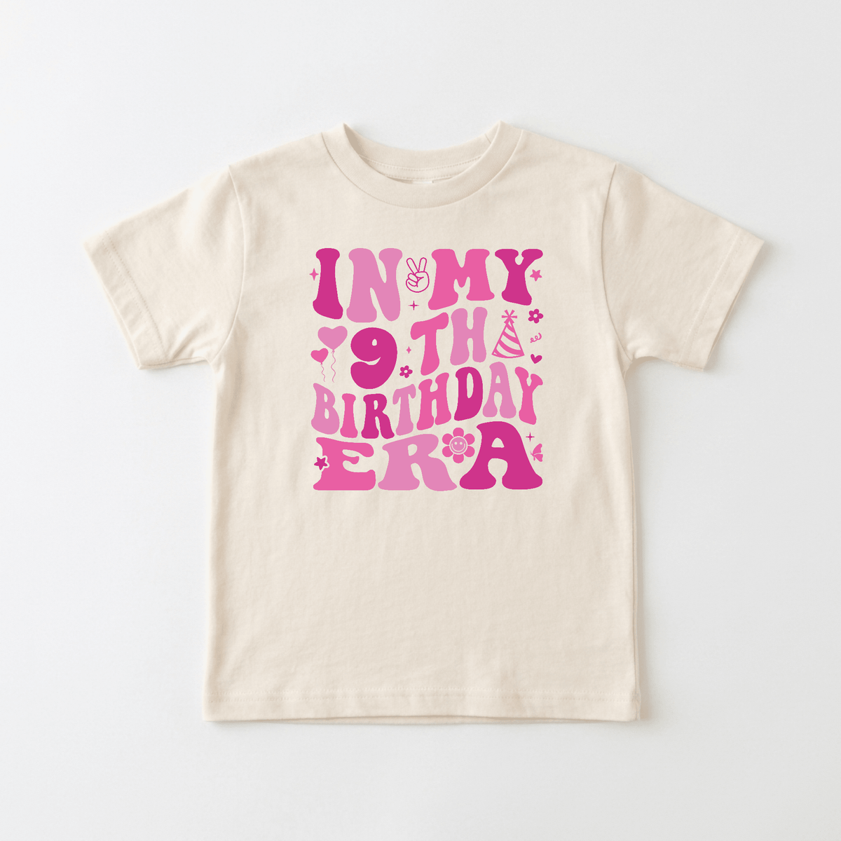 Celebrate in style with the Toodleroos In My 9th Birthday Era Kids Shirt – Retro 9th Birthday Tee! This cream-colored t-shirt features bold pink text that reads “In My 9th Birthday Era,” surrounded by cute icons like stars, a smiley face, and a party hat. It’s the perfect choice for anyone looking for fun and vibrant kids’ birthday shirts!.
