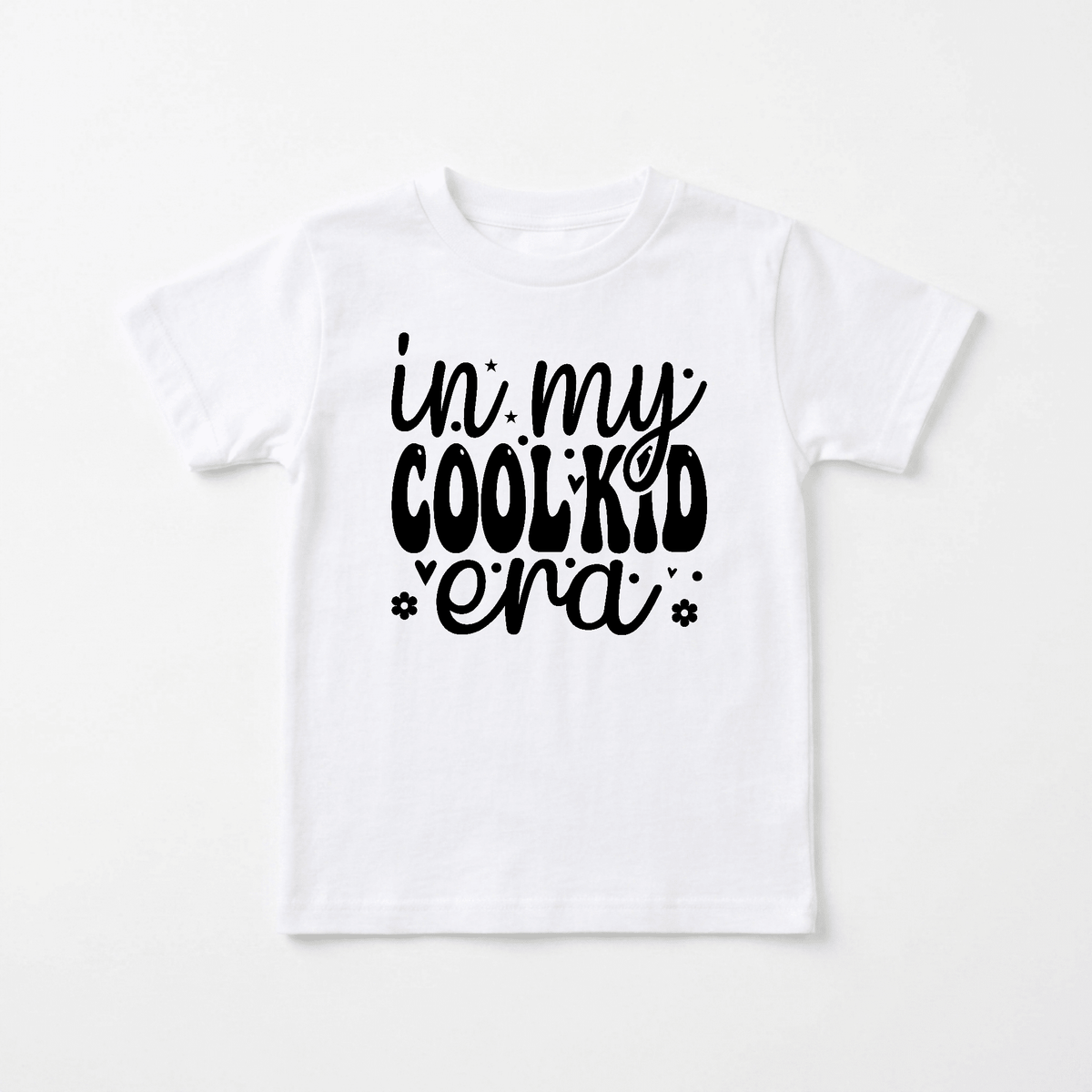 Introducing the In My Cool Kid Era Kids Shirt – Trendy Retro Tee by Toodleroos: a white shirt featuring playful black text that reads “in my COOL KID era” in mixed fonts, surrounded by small stars and flowers. This retro-inspired tee blends nostalgic style with a modern twist, making it perfect for any kid who loves funny shirts and standout fashion.