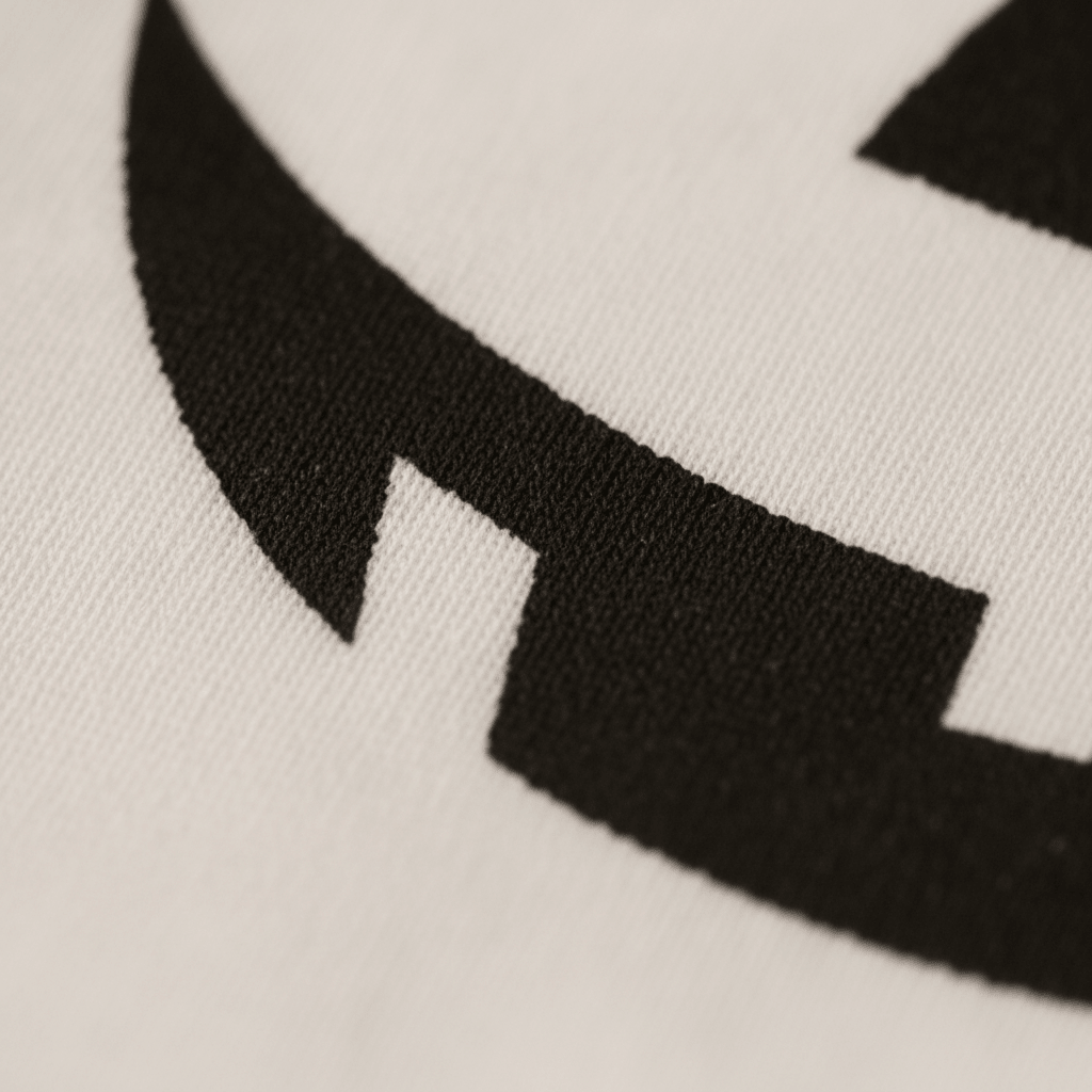 Close-up of a black geometric Jack-O-Lantern face design printed on soft white fabric—highlighting crisp edges and textured material on the Toodleroos Jack-O-Lantern Face Baby Onesie Halloween Bodysuit, perfect for giving your baby’s costume a unique look.