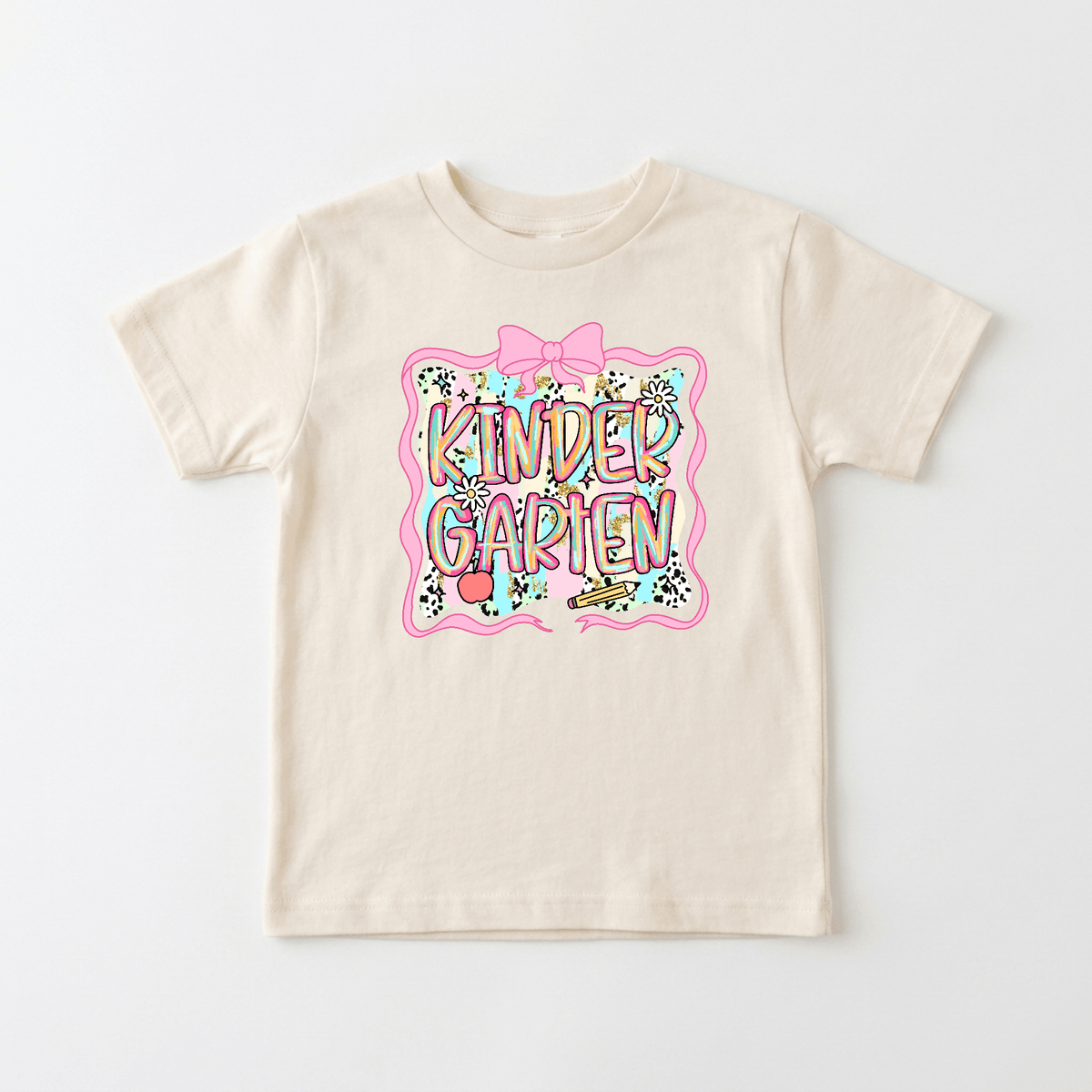 The Toodleroos Kindergarten Youth Tee – Back to School Girls Shirt features a beige color with colorful KINDER GARTEN text, playful flowers and stars, and a large pink bow design in the center—making it the perfect choice for your little one’s first day of school or as an adorable addition to her back-to-school shirts collection.