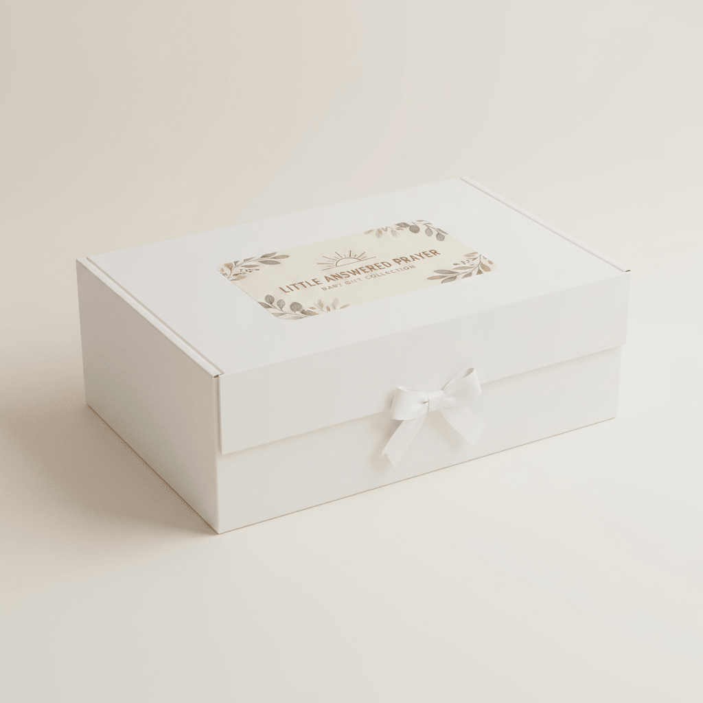 Presented by Toodleroos, the Christian Baby Gift Box – Little Answered Prayer Baby Shower Gift features a white gift box adorned with a petite white bow on its front. The lid is embellished with a beige label decorated with floral accents and the words “Little Answered Prayers.” Ideal as a Christian baby gift or thoughtful baby shower present, this beautifully packaged set makes celebrating life’s blessings even more meaningful. The scene is set against a light, neutral background.
