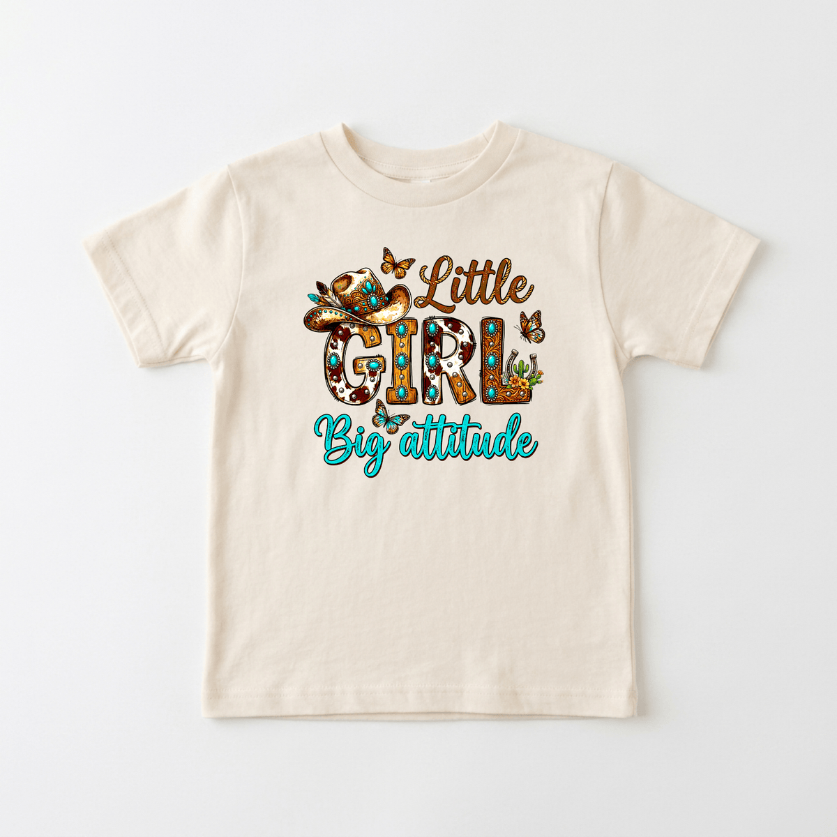 Dress your little one in the Toodleroos Little Girl Big Attitude Kids Shirt – a beige western cowgirl tee featuring vibrant “Little Girl Big Attitude” text, playful flowers, butterflies, and a cowboy hat—perfect for adding some fun flair to your child’s wardrobe.