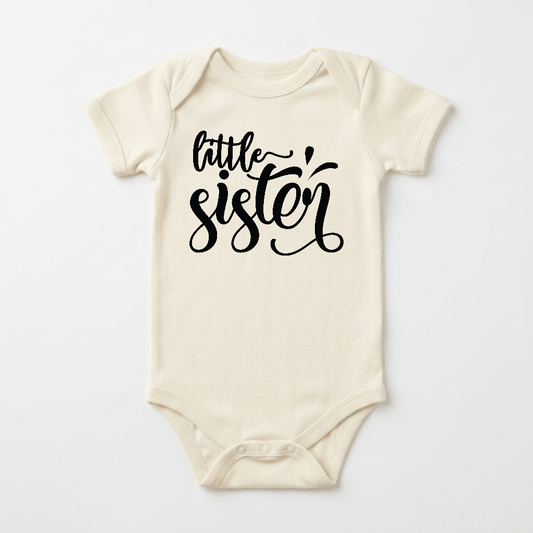 Dress your little one in the Toodleroos Little Sister Baby Onesie – Hand-Lettered Sibling Design, a cream-colored bodysuit featuring “little sister” in black cursive on the front—ideal for sibling outfits and celebrating your newest addition.