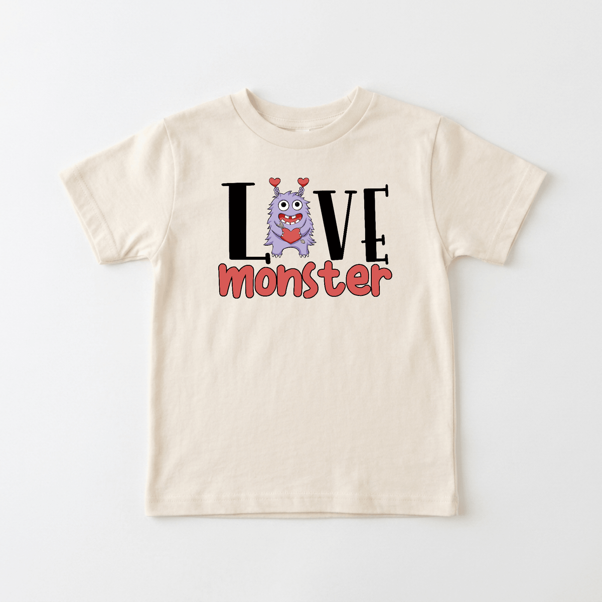 Dress your little one in the Toodleroos Love Monster Toddler Shirt – Valentine’s Day Tee! This adorable beige t-shirt features the word “LOVE,” with the ‘O’ replaced by a cheerful purple cartoon monster sporting heart-shaped antennae. The word “MONSTER” appears below in playful red letters, making this top a sweet and quirky choice for Valentine’s Day or any special occasion.