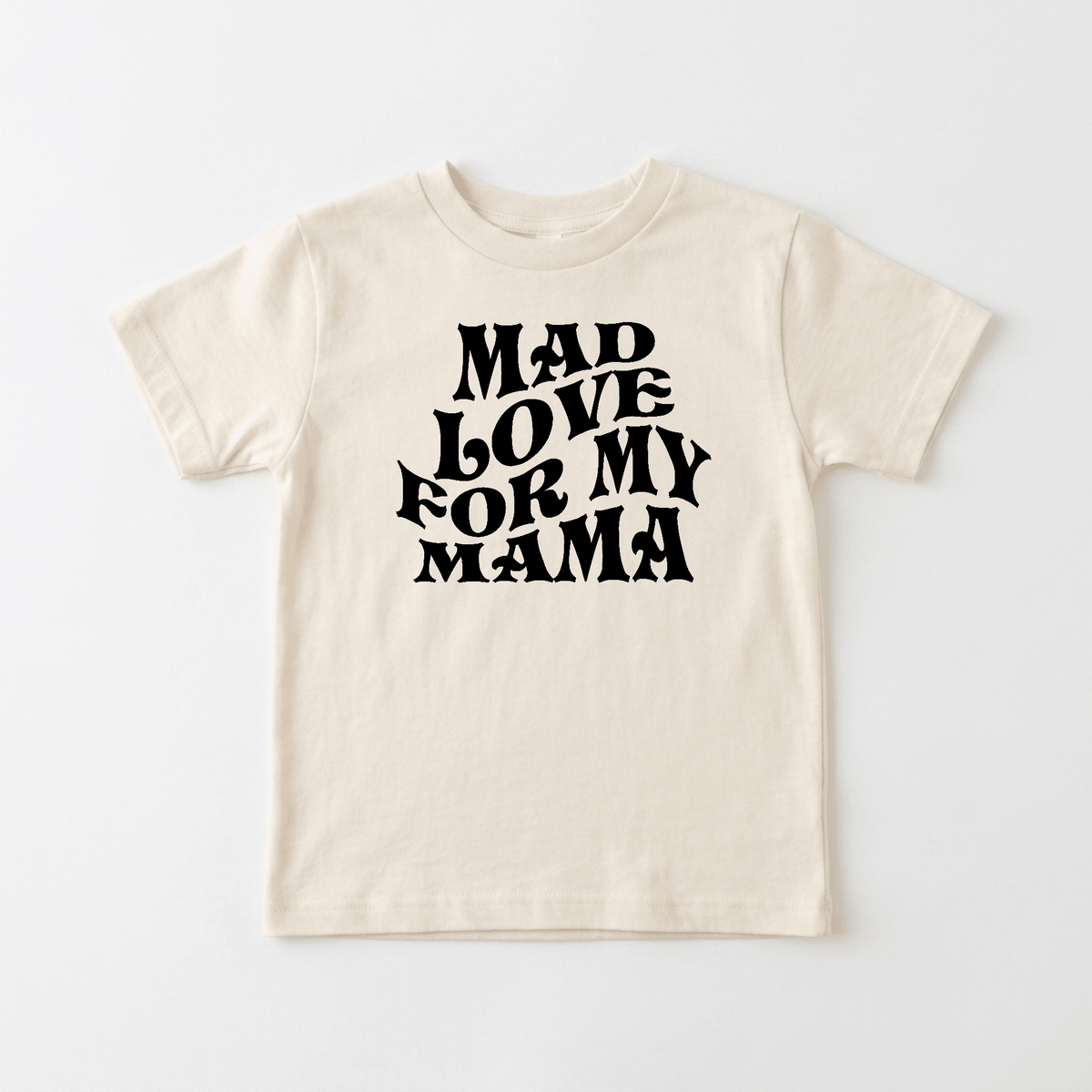 The Toodleroos Mad Love for My Mama Toddler Shirt – Mother’s Day Tee is a beige retro t-shirt for toddlers, showcasing bold, wavy black lettering that says “MAD LOVE FOR MY MAMA,” photographed on a plain white background—an ideal choice for a Mother’s Day toddler shirt.