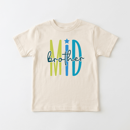 Celebrate your little one’s special place in the family with the Middle Brother Toddler Shirt by Toodleroos! This beige children’s t-shirt features “Mid” in bold green and blue letters (with a star above the “I”) and “brother” in playful black script across the front, making it perfect for sibling announcements or as a unique middle brother shirt. A colorful, fun design that’s ideal for toddlers!.