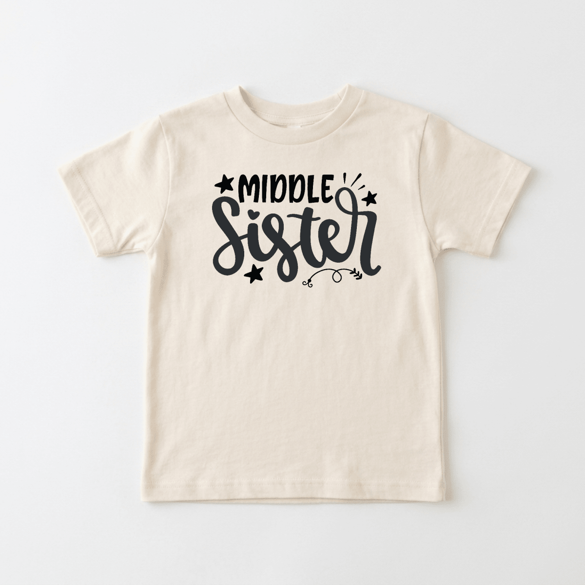 The Toodleroos Middle Sister Toddler Shirt features a fun, hand-lettered “Middle Sister” design in bold black lettering with whimsical stars and swirls, making it the perfect sibling gift or adorable shirt for any toddler.