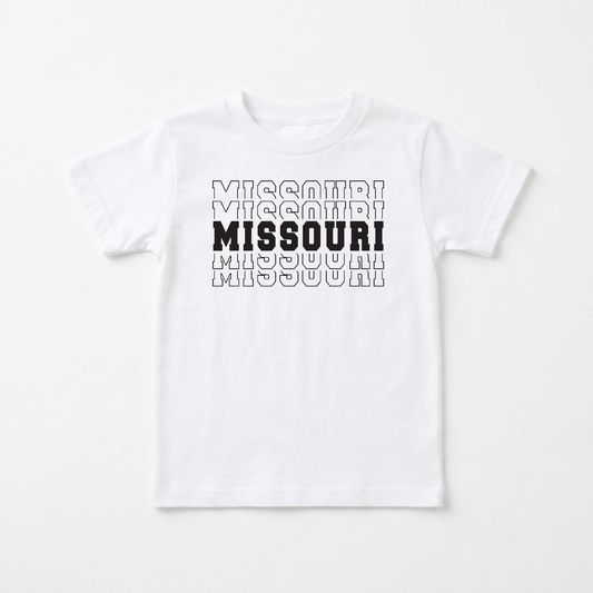 The Toodleroos Missouri Varsity Kids Shirt – State Pride Tee features the word “MISSOURI” printed three times in outlined text, with the center “MISSOURI” in bold, solid black letters—a classic kids’ shirt that celebrates hometown pride. The shirt is displayed flat on a white background.