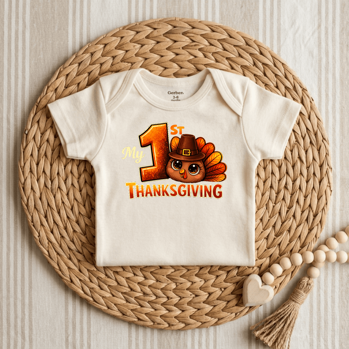 The Toodleroos My 1st Thanksgiving Onesie – Baby Turkey Bodysuit features a charming turkey sporting a pilgrim hat and “My 1st Thanksgiving” text on a cream baby onesie, beautifully displayed on a woven placemat with a wooden beaded accessory beside it—making this adorable outfit the perfect choice for your little one’s first Thanksgiving celebration.