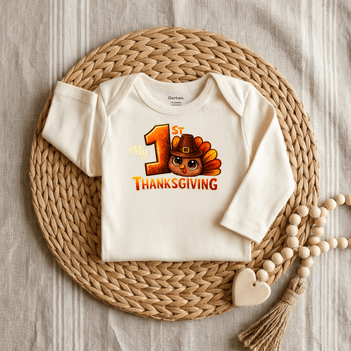 A cream-colored Toodleroos My 1st Thanksgiving Onesie – Baby Turkey Bodysuit featuring a charming turkey design and festive lettering is displayed on a round woven mat with a beaded heart decoration beside it. This delightful baby outfit from Toodleroos is perfect for celebrating your little one’s first Thanksgiving in style.