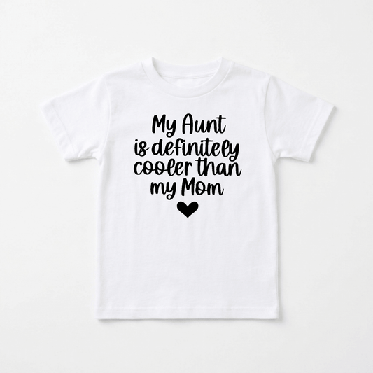 The Toodleroos “My Aunt Is Definitely Cooler Than My Mom Toddler Shirt – Funny Family Tee” features a white t-shirt with black text saying, “My Aunt is definitely cooler than my Mom,” along with a heart symbol underneath. This playful toddler shirt makes an ideal aunt gift and is perfect for any special occasion.