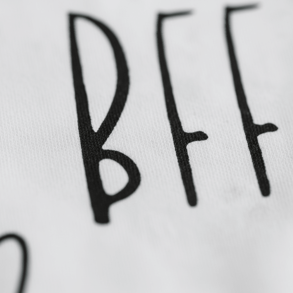 Close-up of black text on white fabric showing the words “My Aunt Is My BFF” in a handwritten style, featured on the Toodleroos My Aunt Is My BFF Baby Onesie – Handwritten Aunt Bodysuit. This adorable aunt-themed bodysuit makes the perfect gift for a baby from their aunt.