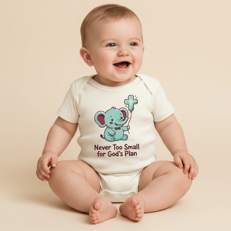A smiling baby sits in a white Toodleroos Never Too Small for God’s Plan Onesie – Faith Bodysuit, featuring an adorable illustration of an elephant holding a cross and the phrase “Never Too Small for God’s Plan”—a perfect baptism gift and piece of faith-inspired baby clothing.