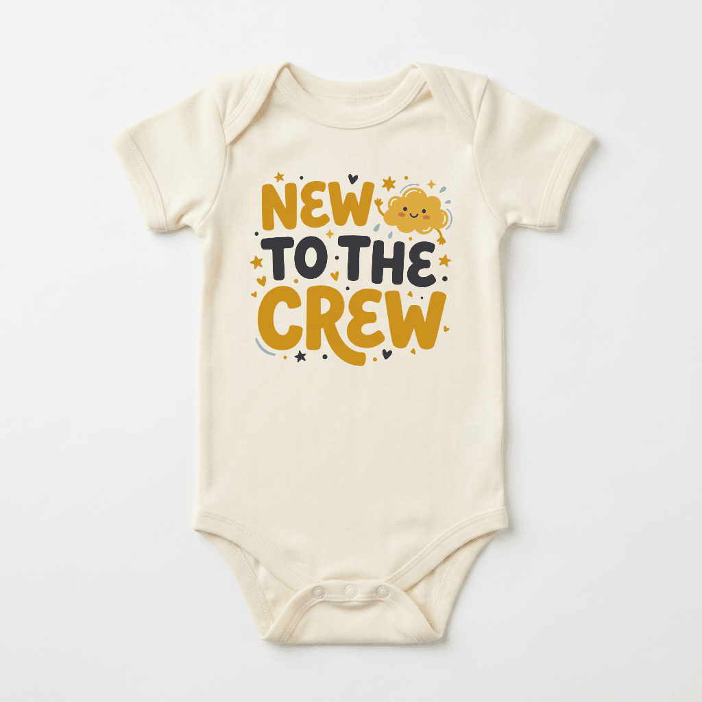 The Toodleroos “New to the Crew Baby Onesie – Announcement Bodysuit” features bold yellow and black lettering with stars, hearts, and a cheerful cloud graphic on a beige background—ideal for baby showers or introducing your little one in style.