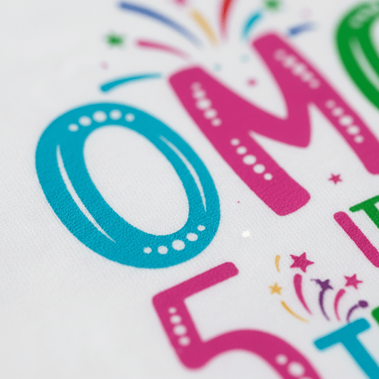 Close-up of the “OMG It’s My 5th Birthday Kids Shirt – Party Tee” by Toodleroos, showing vibrant text and fireworks on fabric, with a bold blue “O” and pink “M,” playful dots, and festive starbursts—an ideal kids birthday shirt for a lively 5th birthday celebration.