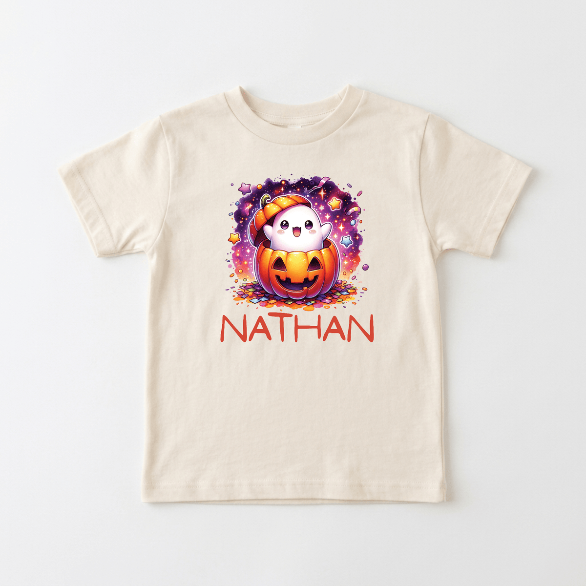 Dress up your little one this Halloween in the Toodleroos Personalized Ghost Pumpkin Toddler Shirt – Halloween Name Tee! This cream-colored tee showcases a cute ghost popping out of a carved pumpkin, surrounded by vibrant sparkles. The shirt is personalized with the name NATHAN printed in bold red letters beneath the design, making it a perfect custom Halloween shirt for your toddler.
